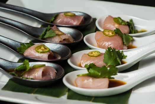 Image of Tuna sushi with Jalapeno on a spoon with soy sauce