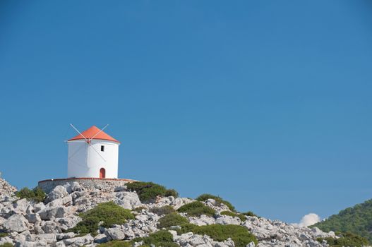 Traditional greek windmill at Panormitis Monastery on the Greek Mediterranean island of Symi, near Rhodes.