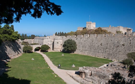 Saint Georges Gate which crosses the dry moats and gives access to Rhodes City. Palace of the Grand Master on horizon.