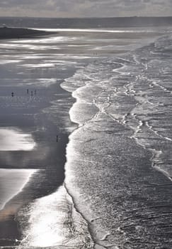 Surfers on the wide expanse of Saunton Sands in North Devon, England