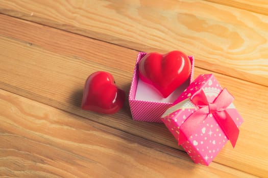 Gift of love. hearty gift. A gift box with a red heart inside. On the wooden floor