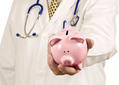 Doctor's hand holding out your piggy bank wanting his payment by taking your savings.  Focus is on the piggy bank
