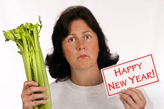 Overweight woman holding a Happy New Year sign and a stalk of celery with the concept of her New Year's resolution is eat healthy and lose weight.