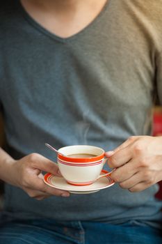 The man wearing grey t-shirt holding coffee cup in his hand in afternoon time