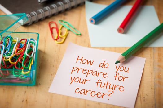 "How do you prepare for your future career" is written on sticky paper with paper clip, color pencil, and pen on wood table