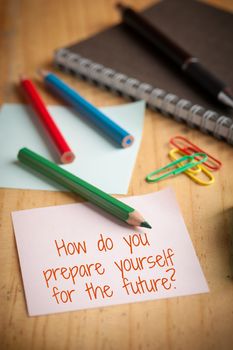 "How do you prepare yourself for the future" is written on sticky paper with paper clip, color pencil, and pen on wood table