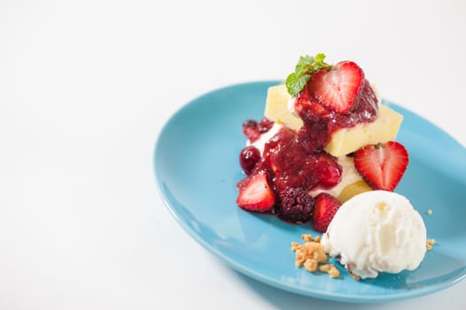 Yellow cake and vanilla ice cream dressed with strawberry sauce on blue dish