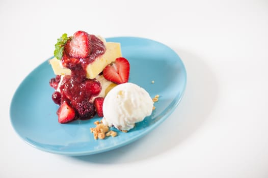 Yellow cake and vanilla ice cream dressed with strawberry sauce on blue dish