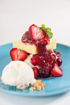 Yellow cake and vanilla ice cream dressed with strawberry sauce on blue dish