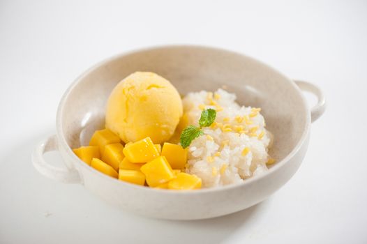 Mango with sticky rice and mango sherbet ice cream in ceramic bowl