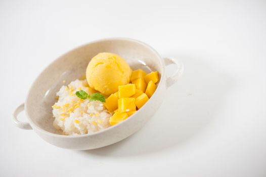 Mango with sticky rice and mango sherbet ice cream in ceramic bowl