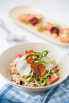 Vegetables and fruits salad with balsamic vinegar and navel orange dressing and smoked striploin ham 1.5 millimeters thickness in ceramic bowl, a modern cusine concept food with another dish of appetizer in background