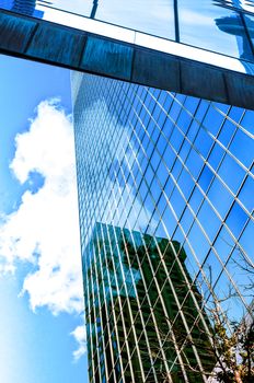 Fragment of a high office building with clouds and reflection