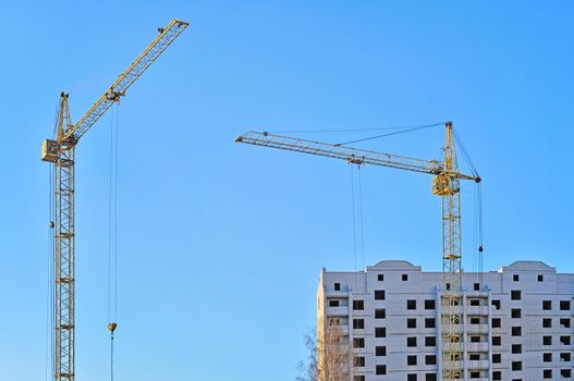 Cranes and building construction on the background of blue sky