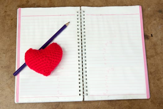 Crochet heart red color and pencil on note book