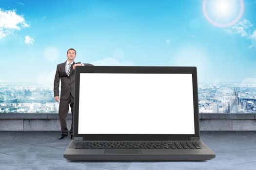 Businessman standing with big laptop with blank screen