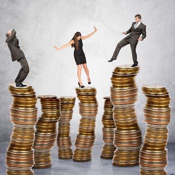 Business people standing on coins stack on grey background