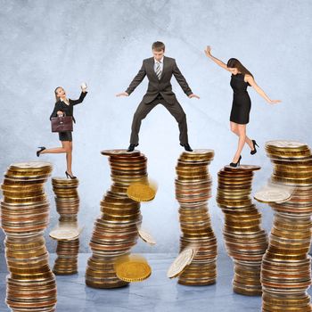 Business people standing on stacks of coins on grey background