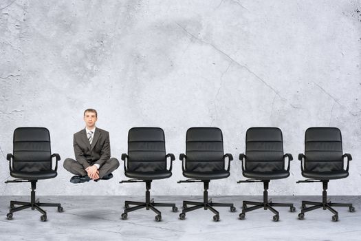 Businessman in lotus posture flying in air on grey background