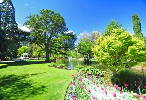 Queenstown Gardens, South Island, New Zealand. A wonderful open public space. Here the lake is seen with the bandstand beyond and with a boarder of tulips in the foreground