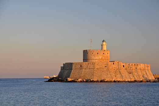 St. Nicholas fortress guards the mouth of Mandraki Harbour on the greek island of Rhodes. The fort, now a lighthouse, stands at the site of the legendary Colossus of Rhodes.