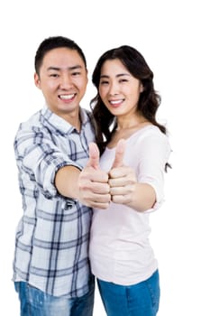 Happy couple showing thumbs up while standing against white background