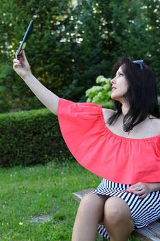 European brunette girl looks at the plate on a park bench