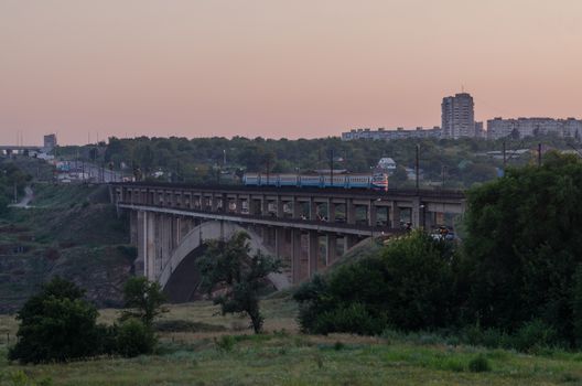 road and rail split-level bridge over the river on a background of blue sky in the city with the train