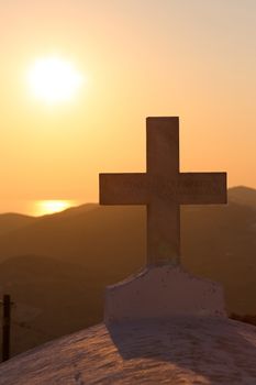 Sunset and the cross of the church at the top of the hill in Chora, Folegandros
