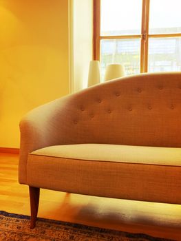 Elegant luxurious sofa in a sunlit room with big window.