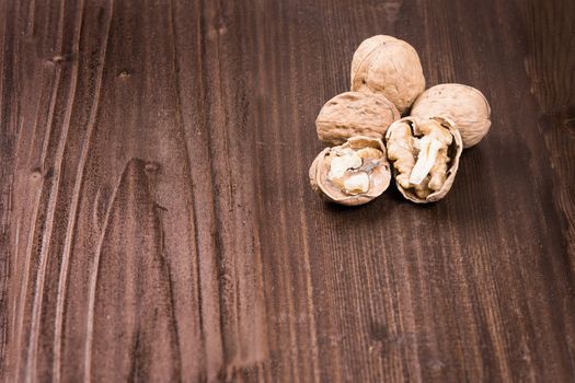 Walnut kernels and whole walnuts on rustic old wooden table