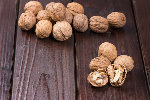 Walnut kernels and whole walnuts on rustic old wooden table