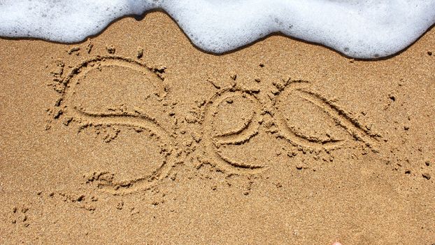 Sea word written on the beach sand.