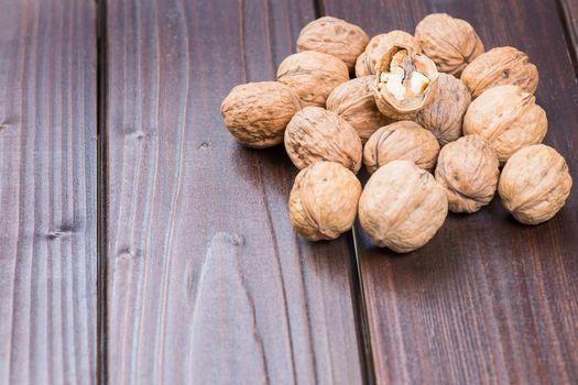 Walnut kernels and whole walnuts on rustic old wooden table