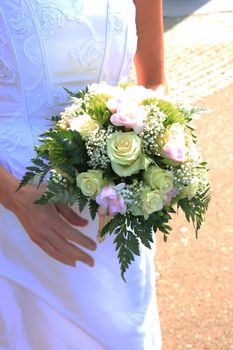 Bride holding her bridal bouquet, ivory roses and pink fresia