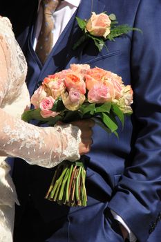 A bride holding her bouquet, roses in various shades of pink