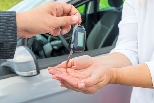 Seller's hand with car keys and hands buyer