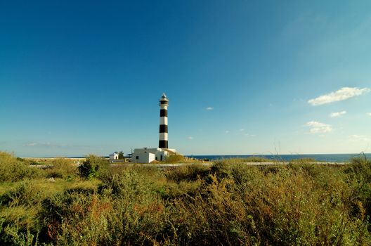 Cap de Artrutx Lighthouse in Summer Sunny Day on Clear Blue Sky background Outdoors. Southwest of Menorca, Balearic Islands