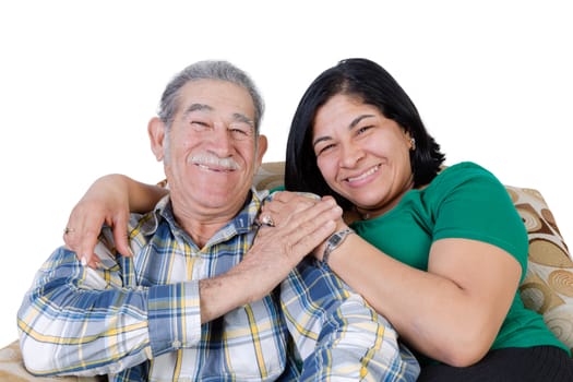 Happy Mexican senior with mustache touching hand of happy daughter sitting together on sofa