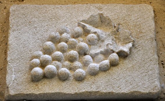 A carved stone bunch of grapes on a building in the old towm of Vaison-la-Romaine, in Provence, France