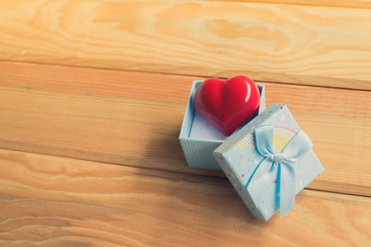 Gift of love. hearty gift. A gift box with a red heart inside. On the wooden floor