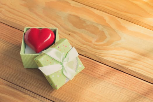 Gift of love. hearty gift. A gift box with a red heart inside. On the wooden floor