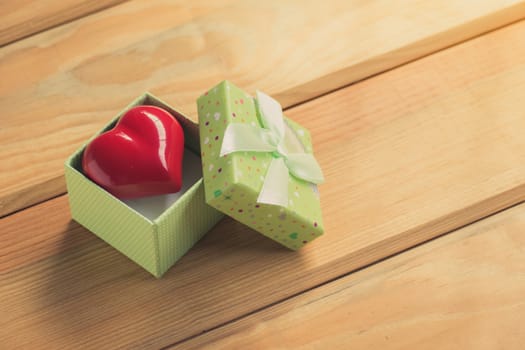 Gift of love. hearty gift. A gift box with a red heart inside. On the wooden floor