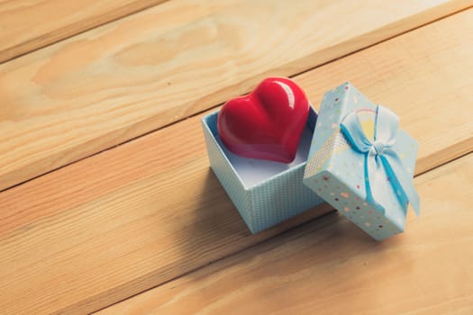 Gift of love. hearty gift. A gift box with a red heart inside. On the wooden floor