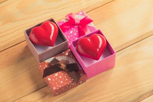 Gift of love. hearty gift. A gift box with a red heart inside. On the wooden floor