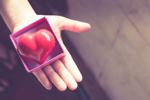 Red Heart in a gift box, in the hands of a girl. valentine background