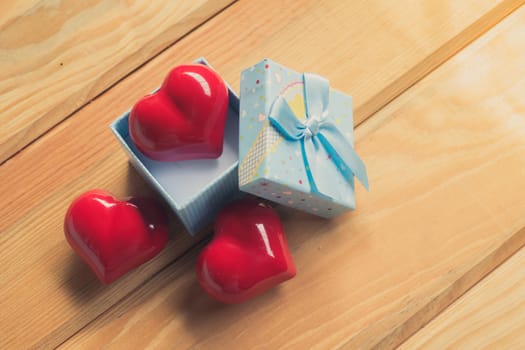 Gift of love. hearty gift. A gift box with a red heart inside. On the wooden floor