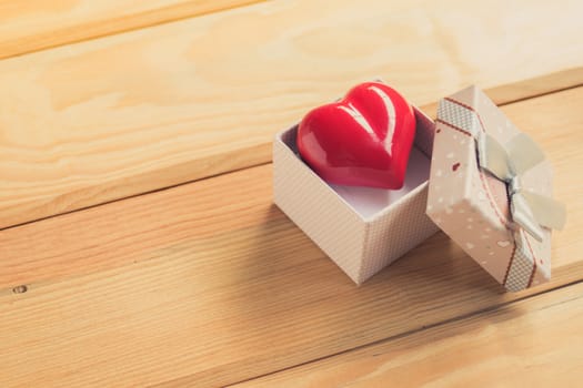 Gift of love. hearty gift. A gift box with a red heart inside. On the wooden floor