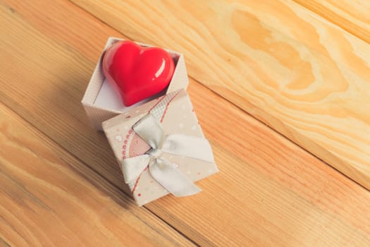 Gift of love. hearty gift. A gift box with a red heart inside. On the wooden floor