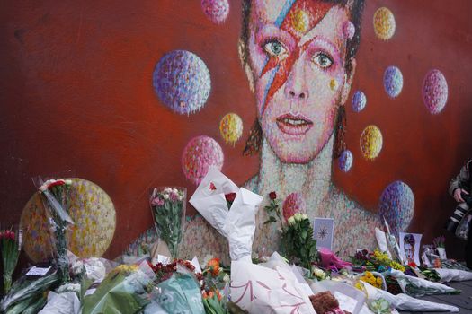 UNITED KINGDOM, London: Fans leave flowers and candles to pay tribute to British singer David Bowie, following the announcement of Bowie's death, in Brixton, south London, on January 11, 2016. British music icon David Bowie died of cancer at the age of 69, drawing an outpouring of tributes for the innovative star famed for groundbreaking hits like Ziggy Stardust and his theatrical shape-shifting style. 